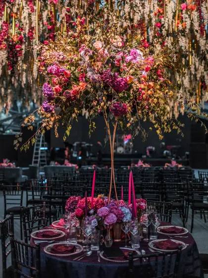 Interior shots of the Bridgerton-themed Sangeet, highlighting the moody lighting, rich velvet furniture, and dramatic floral centerpieces.