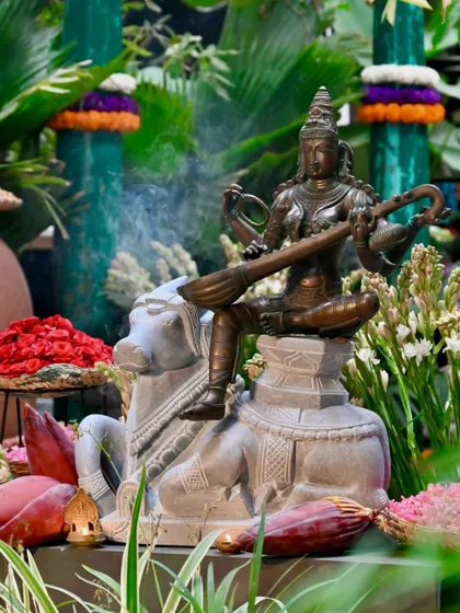 A stunning bronze and stone statue depicting a deity on Nandi, set amidst flowers for the Sankranthi festival. This piece celebrates agricultural abundance and family unity, blending divine art with festive traditions.