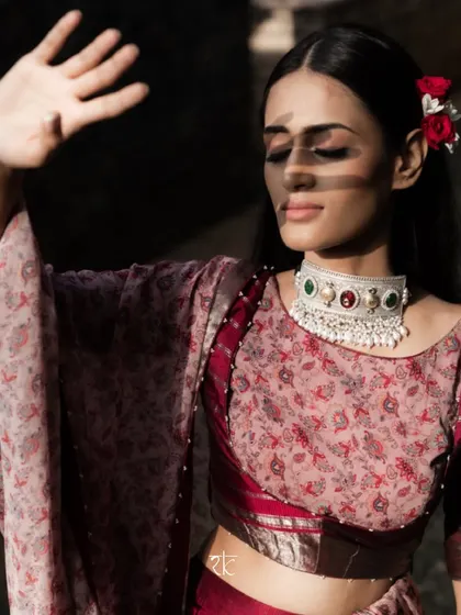 An artistic shot capturing the play of light and shadow on our muse, dressed in the elegant Brick Maroon lehenga set.