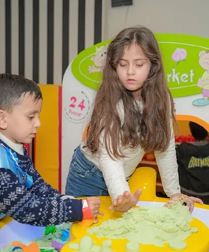 Kids gather around the sand table for some creative and tactile fun.