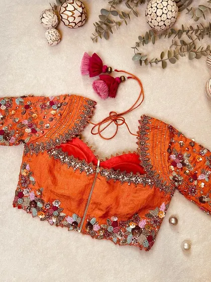 A peach tissue raw silk corset blouse, embellished with Aari, zardosi, and exquisite cut work.