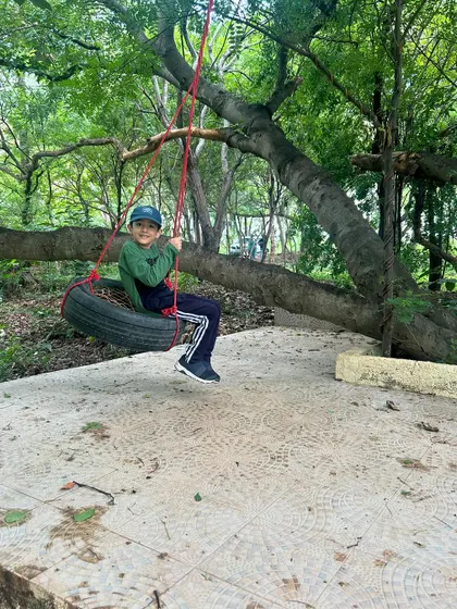 A happy camper enjoying a classic tire swing. Simple outdoor play is at the heart of our philosophy, letting kids just be kids.