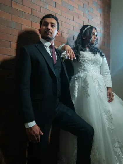 A cool, editorial-style wedding portrait in black and white. The strong poses and dramatic shadows create a high-fashion, modern look.
