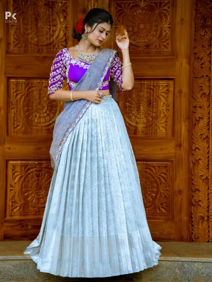 A beautiful half saree in a unique combination of sky blue and purple. The pleated tissue silk lehenga is paired with a heavily embroidered purple blouse.