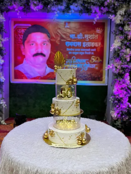 The 50th birthday cake set up at the party venue, right in front of a personalized banner for the birthday person.