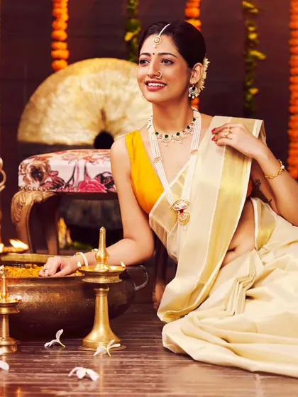 A jewellery campaign with a traditional South Indian theme. The warm lighting from the diyas creates a beautiful, festive glow, highlighting the intricate gold jewellery and the classic Kasavu saree.