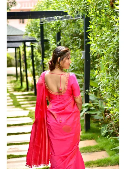 A happy client posing in a beautiful pink saree with a custom blouse. The back design is simple yet elegant.