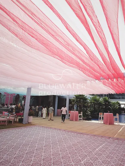 A wide view of the event space, showing the canopy of pink and blue organza drapes creating an airy, colorful ceiling.