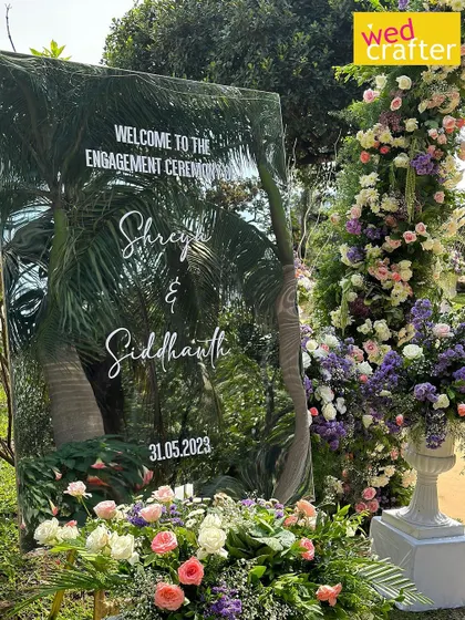 A personalized touch for Shreya and Siddhanth's engagement. A mirrored welcome sign reflects the surrounding greenery, blending modern design with the natural beauty of the garden.