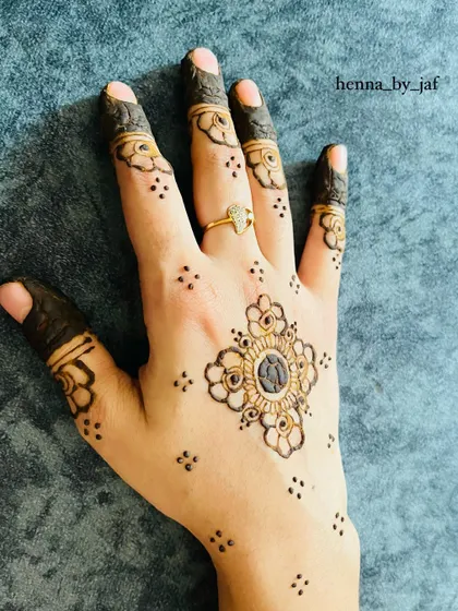 A delicate and symmetrical design with a central floral motif. Small dots and stars are scattered around it, and the fingers have simple flower patterns.