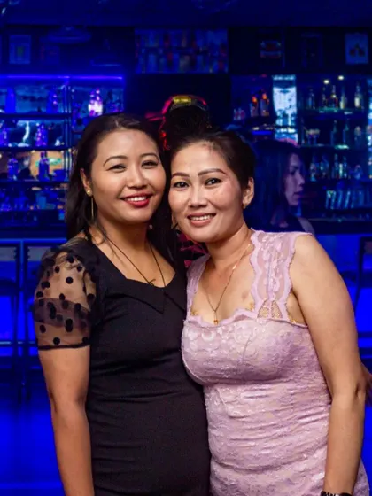 Another lovely shot of two friends enjoying their night. The well-lit bar in the background adds to the atmosphere.