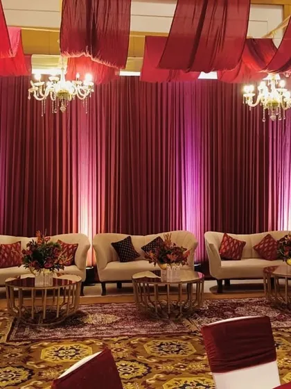 A luxurious lounge area with rich red drapes, plush seating, and elegant chandeliers, inviting guests to unwind in style and comfort.
