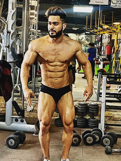 A full-body pose showing the classic X-frame that bodybuilders strive for: wide shoulders, a small waist, and powerful legs.