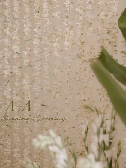 A close-up detail of the floral backdrop from the signing ceremony, showing the texture and delicate nature of the hanging tuberose strings.