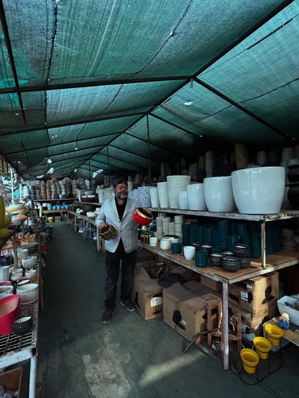 A wide shot of me in our main pot section. You can see the shelves are packed with hundreds of different ceramic pots, giving you an idea of the scale of our collection.