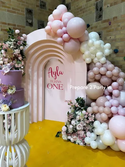 These images highlight the unique elements of this first birthday, including the custom-designed cake plinth and the combination of fresh flowers and balloons for a high-end look.