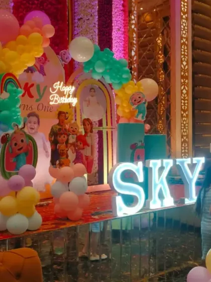 The main stage for the Cocomelon party, featuring character backdrops, a colorful balloon garland, and light-up letters spelling the birthday boy's name.