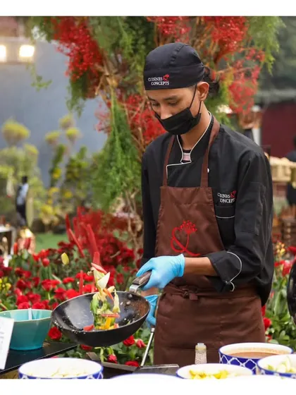 A chef at an outdoor event, tossing fresh ingredients in a pan, showcasing the dynamic cooking process.