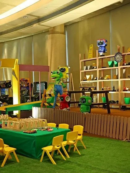 An overview of the Gecko's Garage party, set up like a real workshop and arcade. It features a prize station, kids' activity tables, and various arcade games for entertainment.