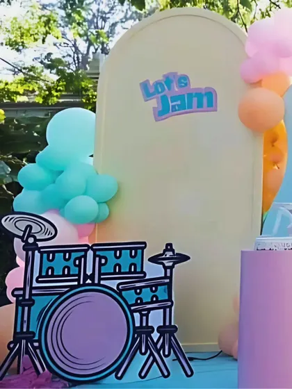 A custom drum set cutout and "Let's Jam" sign add a cool, retro vibe to the music-themed stage, inviting kids to imagine themselves as part of the band.