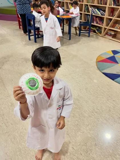 A young scientist proudly displays the eyeball model he made. This is a great example of how we combine art with science education.