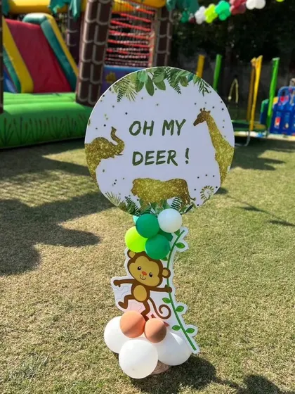 A playful "Oh My Deer!" sign with a monkey cutout, adding a fun touch to the jungle party decor.