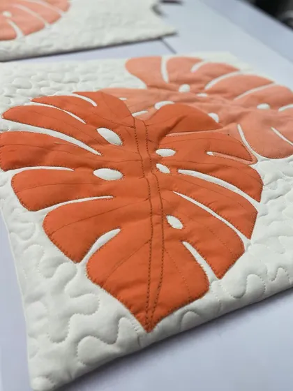 A close-up of the Monstera leaf appliqué, showing the detailed stitching on the veins of the leaf.