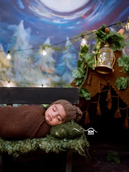 The sweetest smile on this sleeping newborn. We create cozy and imaginative scenes like this woodland camp for your baby's first photoshoot.