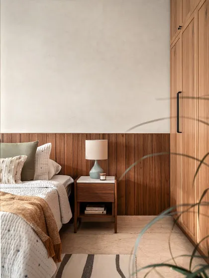 The warmth of wood is a key element in this bedroom. A wood-paneled half-wall serves as a headboard, seamlessly integrating with the built-in wardrobes for a clean, cohesive look.
