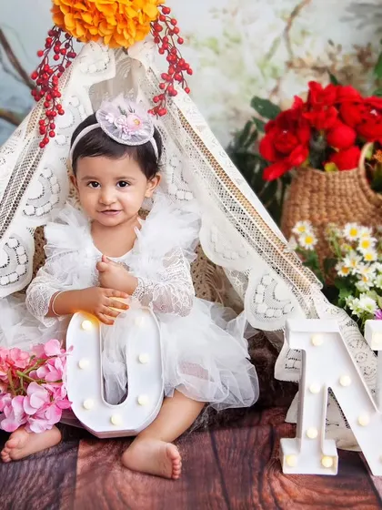 Posing proudly with her 'ONE' letters. This is a classic shot to celebrate a very special first birthday.