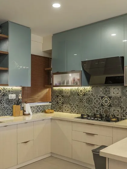 The combination of teal lacquered glass cabinets and a patterned backsplash makes this kitchen a standout feature of the home.