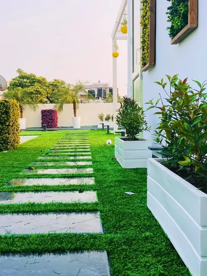 A different project, showing a pathway of stone slabs set into an artificial lawn, with clean white planters adding a modern touch.