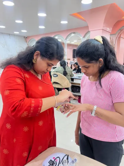 A trainer giving one-on-one feedback to a student during a nail practice session.