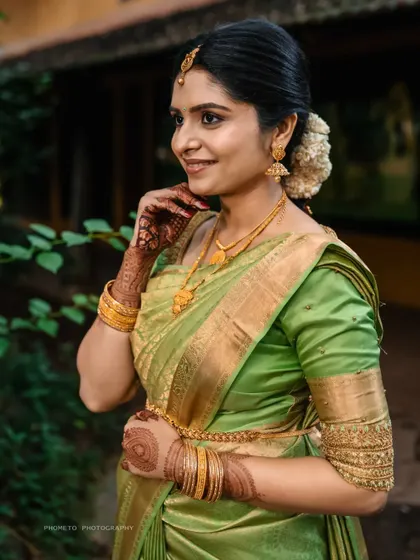 A beautiful portrait of the bride-to-be, her green saree and gold jewelry glowing in the natural light.