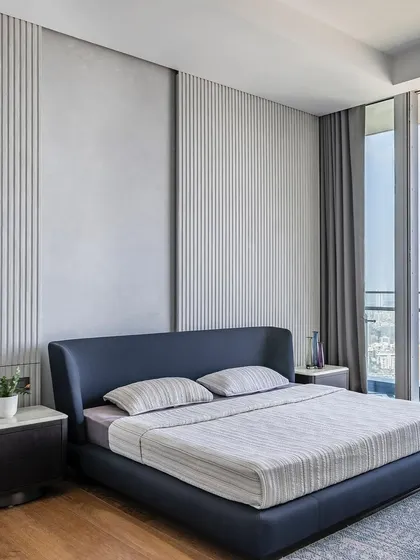 This view showcases the bedroom's connection to the outdoors, with floor-to-ceiling windows flooding the space with natural light. The minimalist design ensures the focus remains on the expansive view and the room's tranquil atmosphere.