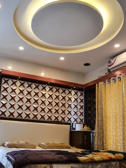 An alternate view of the bedroom with the 3D accent wall, this time showing the circular false ceiling design. The recessed ring light provides soft, even illumination throughout the room, complementing the geometric wall pattern.