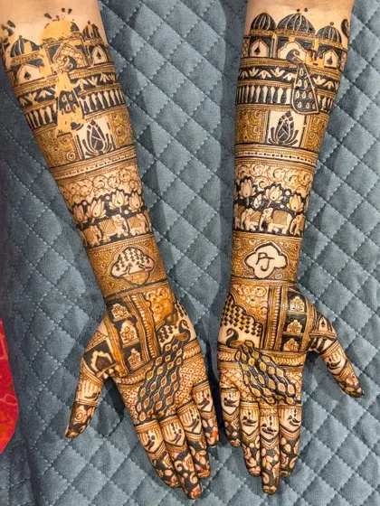 This full-arm bridal design is a masterpiece of symmetry and detail. It features personalized initials, elephant motifs, and palace-inspired architecture, all woven together with classic jaali (net) patterns.
