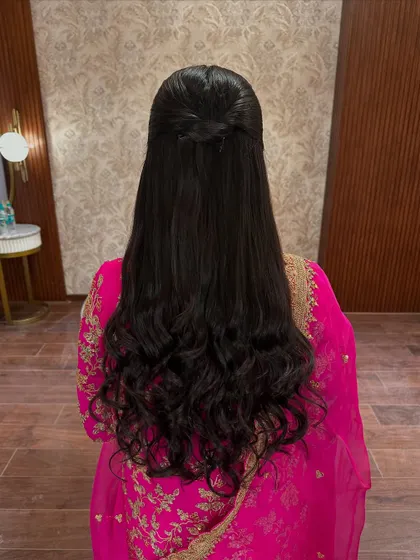 A classic and sleek pulled-back hairdo with voluminous curls at the end. This timeless style is perfect for any wedding event, from a puja to the reception.