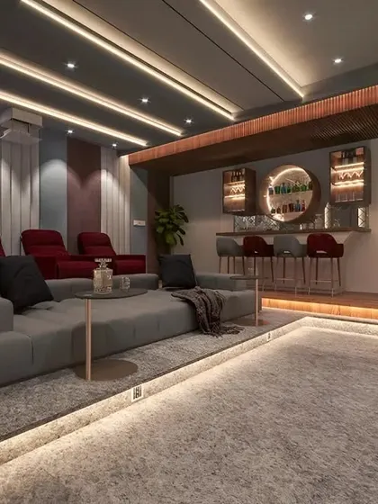 A high-end home entertainment room featuring plush recliner seats, a comfortable sofa, and a built-in bar. The floor and ceiling lighting create a sophisticated and immersive atmosphere.