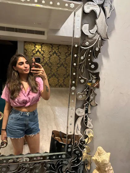 Another selfie, this time in a casual pink shirt and denim shorts.