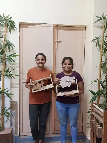 Two students with the shelves they built, which feature fun elephant and pig cutouts. This is a great way to personalize a simple project.