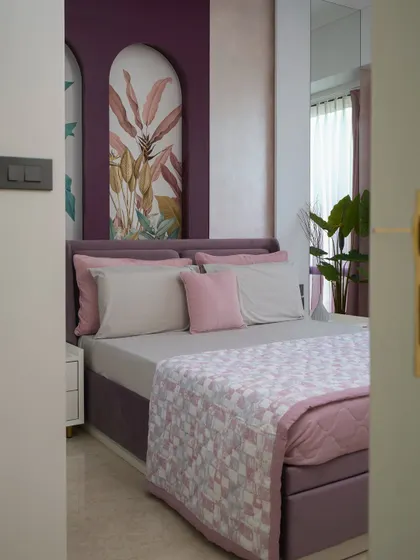A tropical escape in the heart of South Mumbai. This guest room blends resort-style relaxation with urban sophistication, featuring tropical-inspired wallpaper and a soft palette of whites, blush pinks, and muted purples.