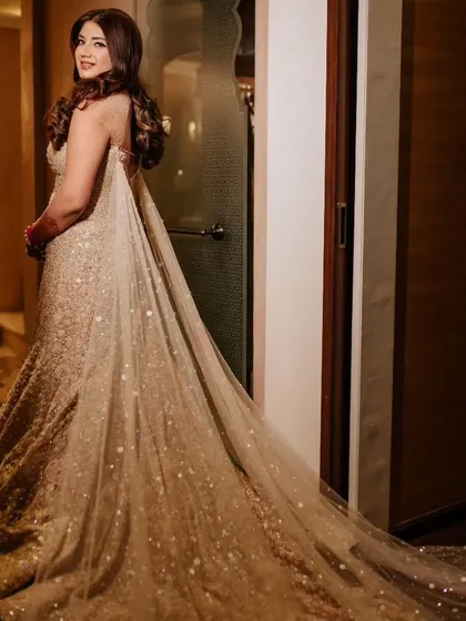 A side view of the bride's cocktail gown, emphasizing the dramatic and elegant cape that adds movement and glamour to her look.