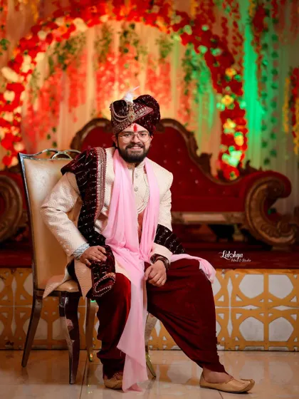 A relaxed, full-length portrait of the groom seated. His comfortable pose and happy smile show his personality and style on his big day.