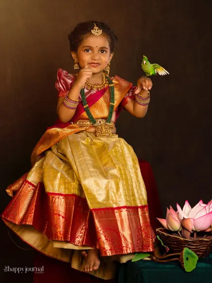 A little girl in a traditional silk outfit, with a friendly parrot perched on her hand. A magical and unique portrait combining nature and culture.