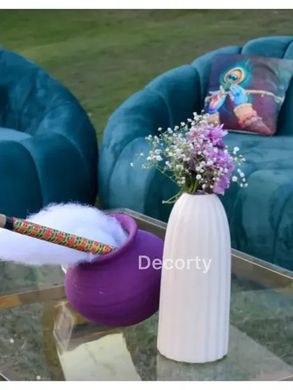 A cozy seating area with Krishna-themed cushions and a centerpiece featuring a pot of 'makhan' and a flute.