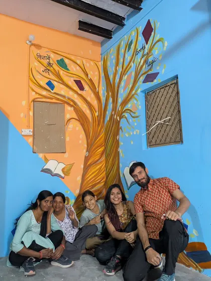 Here we are, the team and I, sitting under the 'Tree of Knowledge' mural we painted at the resource center in Kirari village. The idea was to make learning feel magical, with books growing on trees. It was a joy to bring this concept to life and create a welcoming space for the children.