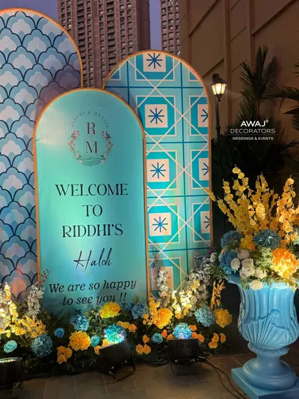 The welcome area at night, with spotlights highlighting the vibrant colors of the flowers and the intricate patterns of the decor.