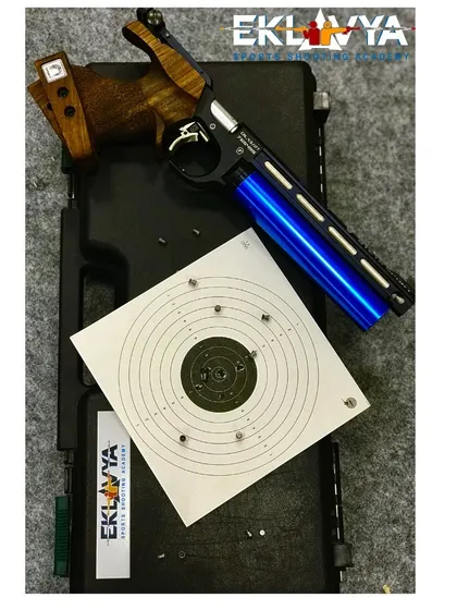 A close-up of a high-precision air pistol and a target sheet showing a tight grouping of shots. We provide access to Olympic-grade equipment to help every shooter achieve their best performance.
