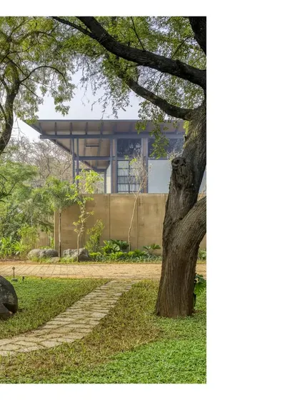 A view of the Lakeshore house through the trees. The design uses a combination of a prefabricated metal skeleton and rammed earth walls to create a home that is both precise and deeply connected to its site.